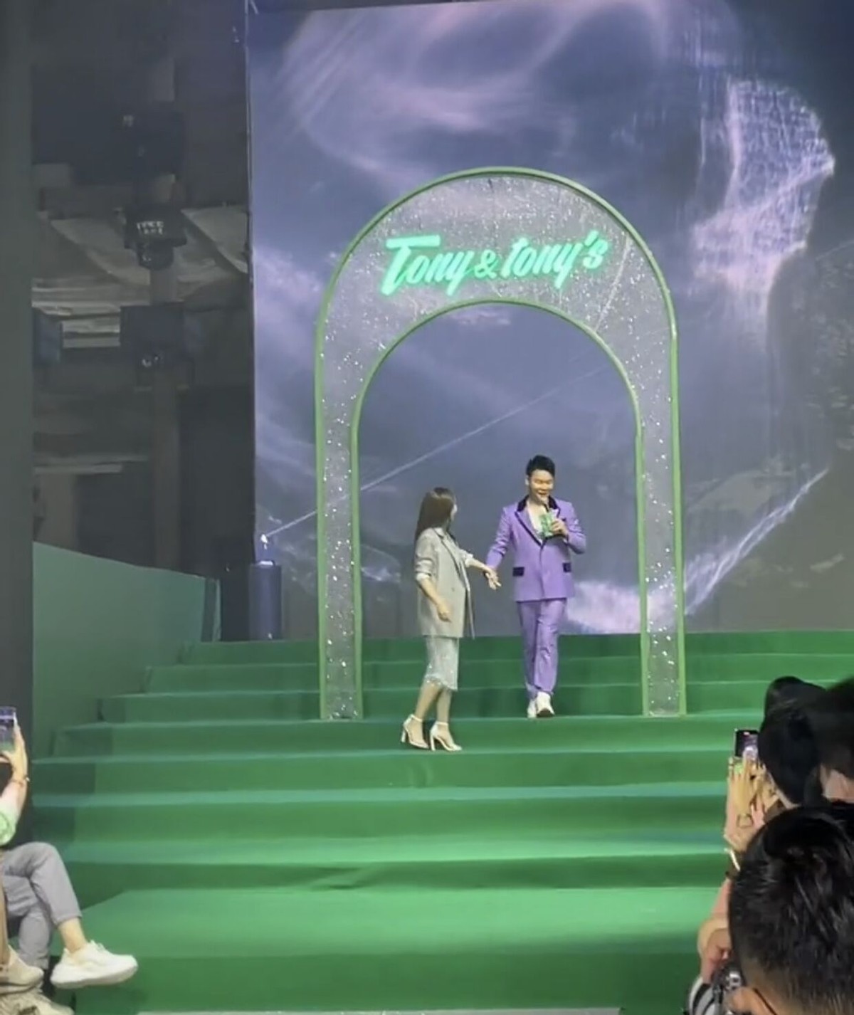 李菲儿牵着男主持人手下楼梯，不慎摔倒在地，被男生搂入怀安慰