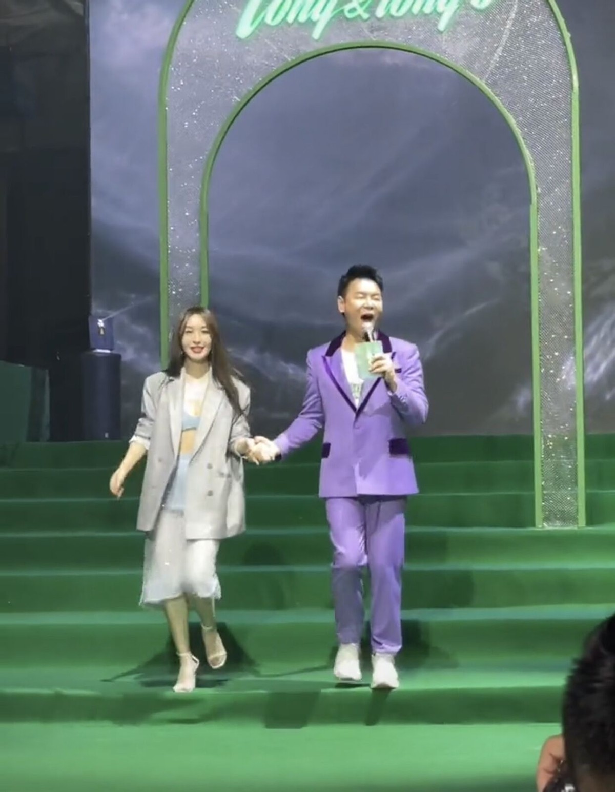 李菲儿牵着男主持人手下楼梯，不慎摔倒在地，被男生搂入怀安慰