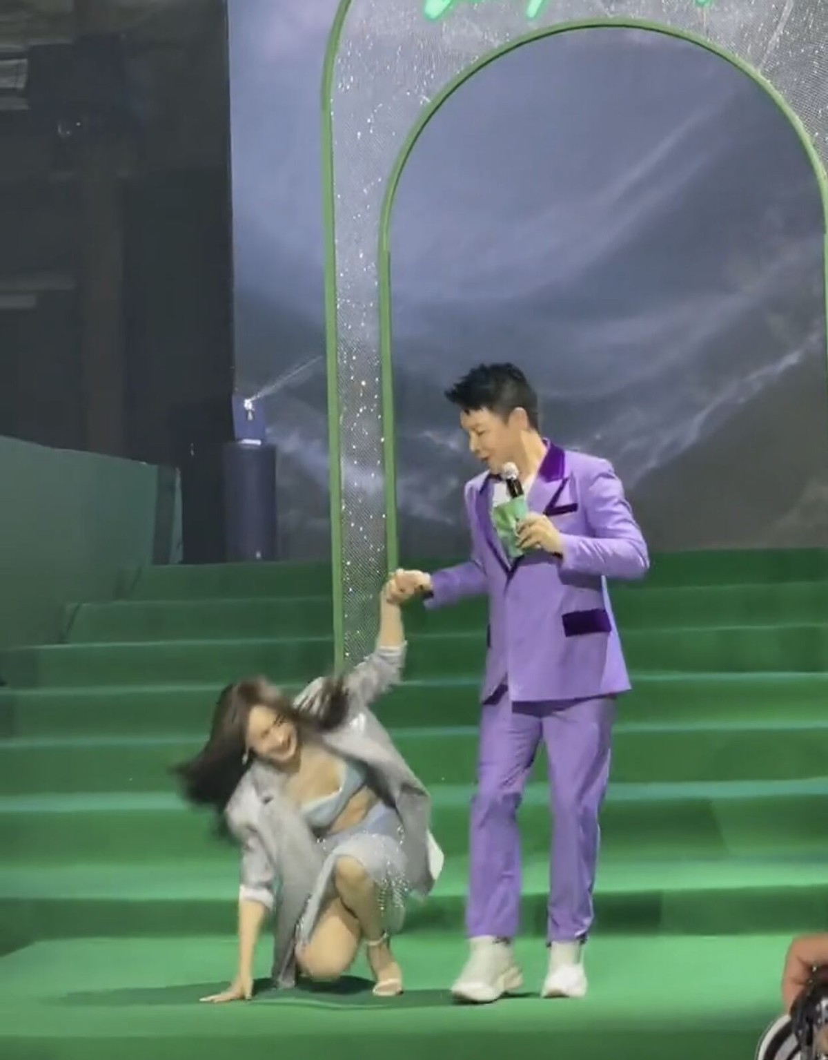 李菲儿牵着男主持人手下楼梯，不慎摔倒在地，被男生搂入怀安慰